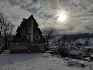 Cîrlibaba NouăCabana de pe stanca - hotel的雪中的房子,天空中阳光