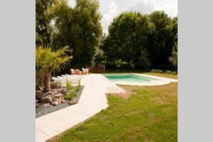 ErnesCoeur de Combray (Ifs appartment)的一座有树木和草地的庭院内的游泳池