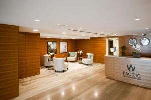 拉斯阿尔卡麦2 Bedroom Deluxe Beach Apartment Al Marjan的一个带白色椅子的候客室和前台的客厅