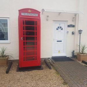 埃尔森汉姆Stansted Lodge Guest House的房屋前的红色电话亭
