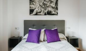 希洪Apartamento MyM2的一间卧室配有一张带紫色枕头的床