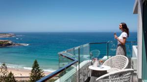 悉尼Crowne Plaza Sydney Coogee Beach, an IHG Hotel的站在海滩景阳台上的妇女