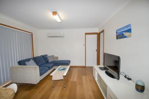 凯阿玛Kiama Coastal Escape的客厅配有蓝色的沙发和电视