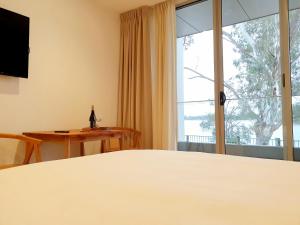 纳甘比尼冈比海滨汽车旅馆的客房设有一张床和一个带桌子的窗户