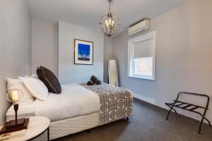 霍巴特City Retreat Hobart的一间卧室配有一张床、一张桌子和一个吊灯。