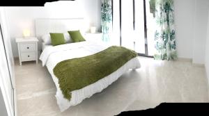 圣路易斯·德·萨比尼尔2 bedrooms appartement with sea view shared pool and furnished garden at Malaga 2 km away from the beach的白色卧室配有一张带绿毯的床