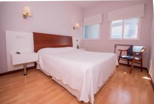 利亚内斯萨布隆酒店的卧室配有一张白色大床和一把椅子