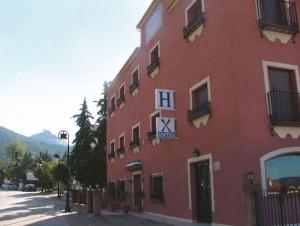 OrceraHostal Rural La Montería的一座红色的建筑,旁边有一个钟