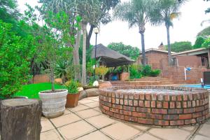 比勒陀利亚Upmarket Villa with pool & lush garden的一座砖砌的喷泉,庭院里种着树木,房子里