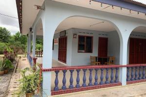 Kampong Bukit KatilBella Homestay Melaka的白色的房子,设有阳台和桌子