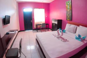 鲁滕Hotel FX72 Ruteng的卧室配有一张带粉红色墙壁的大床