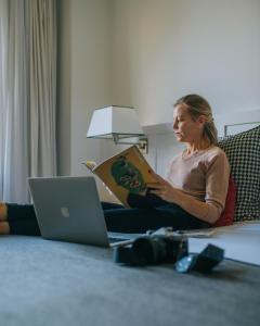 巴塞罗那Gallery Hotel 4 Sup的坐在地板上的女士用笔记本电脑读书