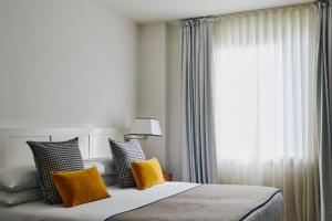 巴塞罗那Gallery Hotel 4 Sup的一间卧室配有一张带黄色枕头的床和一扇窗户