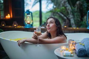 圣卢西亚马卡卡塔纳湾山林小屋的坐在浴缸里拿着一杯葡萄酒的女人