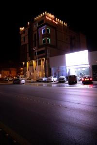 哈费尔巴廷فندق بــــاســــيل的一座有汽车在晚上停在街上的建筑