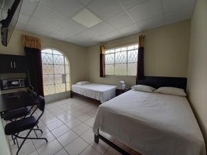 皮乌拉Kira's House的一间卧室配有两张床、一张桌子和两个窗户。