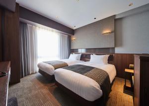 福冈Hotel Trad Hakata的酒店客房设有两张床和窗户。