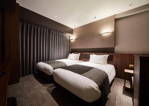 福冈Hotel Trad Hakata的酒店客房设有两张床和窗户。