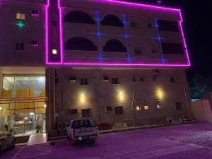 延布Al Fanar Al Alamaya 3- Hay'aa Malakeya entrance的建筑的侧面有紫色的灯