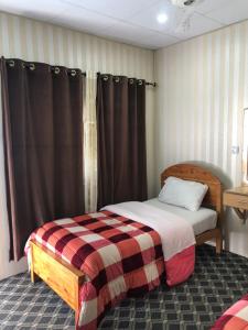 吉尔吉特Madina Hotel 2的一间卧室配有一张带 ⁇ 子毯子的床