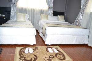 莫希Panone Hotels - King'ori Kilimanjaro Airport的客房内的地板上配有两张床和拖鞋