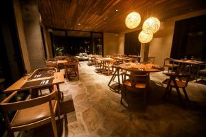 伊卡莱Makena Hotel的餐厅设有木桌和椅子及灯