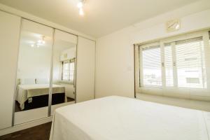 圣保罗Apartamento aconchegante com estacionamento na 25 de março的白色卧室配有床和镜子