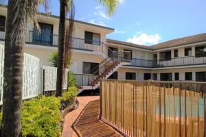 黄金海岸Gold Coast Inn的一座带木栅栏和棕榈树的建筑