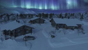 萨利色尔卡Sielikkö Aurora Log Apartments的停在小屋旁边的雪地里的一个汽车