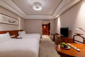 杭州杭州索菲特西湖大酒店的酒店客房设有两张床和一张带一碗水果的桌子。