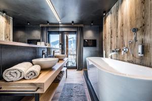 瓦格赖恩ALMMONTE PRÄCLARUM SUITES Design Hotel的一间带大浴缸和两个盥洗盆的浴室