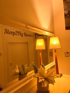 汉堡Sleep2Fly Hamburg-Airport的一间带镜子、灯和鲜花的卧室