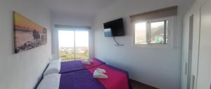 弗龙特拉Buenavista的一间卧室设有紫色的床和窗户