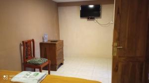 庞越Hotel Nur Cahaya - Syariah的一间卧室配有梳妆台和墙上的电视
