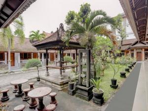 登巴萨SUPER OYO 3261 Hotel Ratu的庭院设有带桌子和棕榈树的凉亭