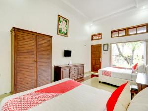 登巴萨SUPER OYO 3261 Hotel Ratu的一间卧室设有两张床、一个梳妆台和窗户。