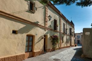AvinyonetCal Mestre Casa Rural的门口鲜花盛开的古老建筑中的小巷