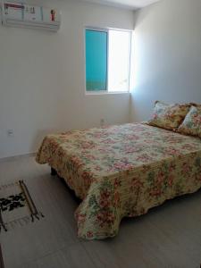 雅克南Duplex Paraíba Litoral Sul Jacumã Acesso as Melhores Praias do Brasil的一间卧室配有一张带花卉床罩的床和窗户。