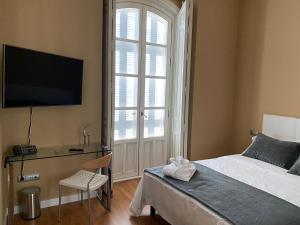 利纳雷斯HOTEL CASABLANCA BOUTIQUE的一间卧室配有一张床、一张书桌和一台电视