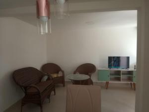 雅克南Duplex Paraíba Litoral Sul Jacumã Acesso as Melhores Praias do Brasil的客厅配有椅子、桌子和电视