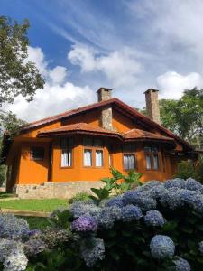 卡曼杜卡亚Pousada Opas Haus的一座橘色房子前面有鲜花