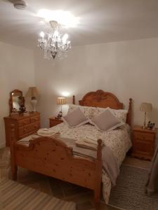 莱特肯尼Kiltoy Cottage, Cosy 2 bedroomed Gate Lodge Cottage的一间卧室配有一张木床和吊灯。