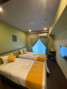 宫古岛HOTEL Fit in Miyakojima的酒店客房设有两张床和电视。