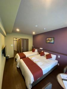 宫古岛HOTEL Fit in Miyakojima的酒店客房设有两张床和紫色墙壁。