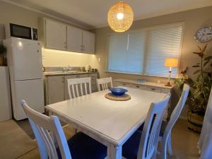 陶朗加Feel at Home的厨房配有白色的桌椅和白色的冰箱。