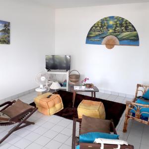 勒穆莱Appartement de 2 chambres avec vue sur la mer et jardin clos a Le Moule a 1 km de la plage的客厅配有椅子和平面电视