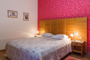 帕兰加Hotel Vila Diemedis的一间卧室配有一张带粉红色墙壁的大床