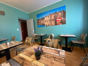 古尔奈昂布赖诺曼底酒店的餐厅设有桌椅,墙上挂有绘画作品
