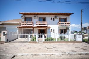 托雷斯Casa da Praia Pousada - Guesthouse的前面有白色围栏的白色房子