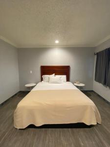 洛杉矶Sandman Motel的卧室配有一张带两张桌子的大型白色床